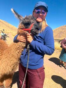 a woman is holding a llama on a mountain at Hacienda Esmeralda in Ñuñoa +6 photos