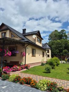 a house with flowers in the yard at Mlynski in Mykulychyn