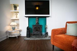 a living room with a fireplace with a television above it at Castle Grant - 4 Bed Cottage in Gardenstown in Gardenstown