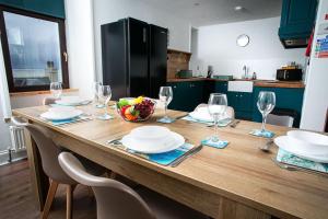 a wooden table with plates and wine glasses on it at Castle Grant - 4 Bed Cottage in Gardenstown in Gardenstown