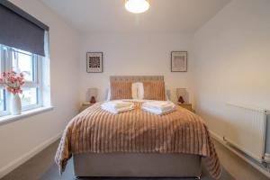 a bedroom with a bed with two towels on it at Lendrick House-Spacious 3 Bed House in Falkirk in Polmont