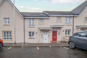 a house with a red door in a parking lot at Lendrick House-Spacious 3 Bed House in Falkirk in Polmont