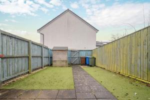 a large white building with a wooden fence at Lendrick House-Spacious 3 Bed House in Falkirk in Polmont