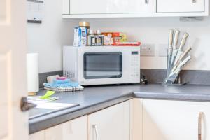 a microwave sitting on top of a kitchen counter at Lendrick House-Spacious 3 Bed House in Falkirk in Polmont +34 photos