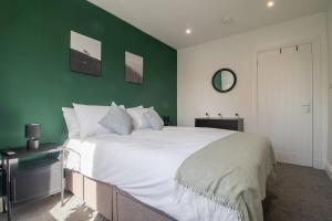 a bedroom with a large white bed with a green wall at Highfield Apartment- 2 Bed in Motherwell close to centre in Motherwell
