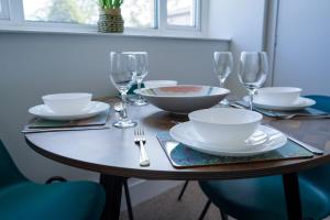 a wooden table with plates and wine glasses on it at Park House - 3 bedroom in Portsoy