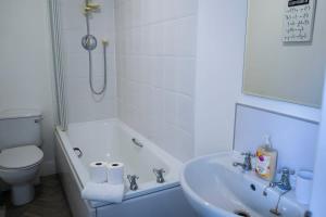 a bathroom with a tub and a toilet and a sink at Park House - 3 bedroom in Portsoy