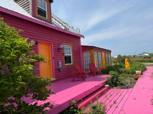 ein rotes Haus mit einer rosa Terrasse mit Stühlen darauf in der Unterkunft La Forillonne in Gaspé
