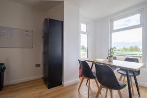 a dining room with a table and chairs and a black refrigerator at Alexandra Apartment - Single Room #1 in Falkirk