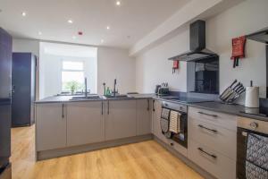 a large kitchen with stainless steel appliances and wood floors at Alexandra Apartment - Single Room #1 in Falkirk