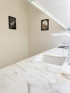 a white kitchen with a sink and two pictures on the wall at Gato street, Private rooms in Madrid
