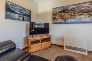 a living room with a couch and a flat screen tv at Whakatā in Te Anau
