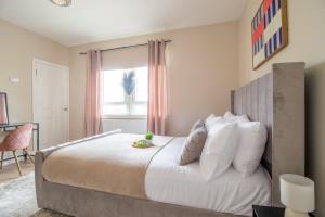a bedroom with a bed with white pillows and a window at Mitchell Apartment in Airdrie
