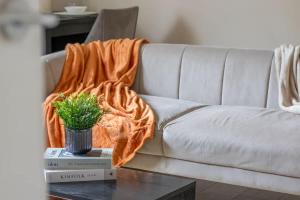 an orange blanket on a couch with a plant on a table at Mitchell Apartment in Airdrie