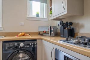 a kitchen with a washing machine and a stove at Mitchell Apartment in Airdrie