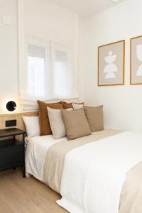 a white bedroom with two beds and a table at Carvajal Street, Private rooms in Madrid