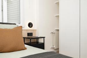 a bedroom with a bed and a table with a clock at Carvajal Street, Private rooms in Madrid +9 photos