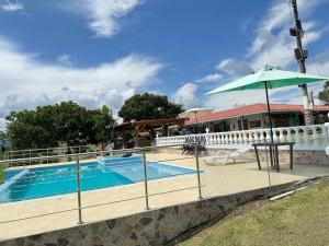 a swimming pool with an umbrella next to a building at El Rincón del Sol y Luna in Quimbaya +12 photos