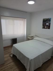 a bedroom with a white bed and a window at Piso vacacional YaraMaya in Carballino +1 photo