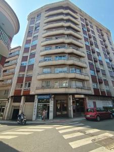 a tall building with a car parked in front of it at Piso vacacional YaraMaya in Carballino