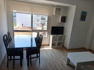 a dining room with a table and chairs and a window at Piso vacacional YaraMaya in Carballino