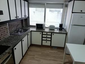 a kitchen with white cabinets and a sink and a window at Piso vacacional YaraMaya in Carballino