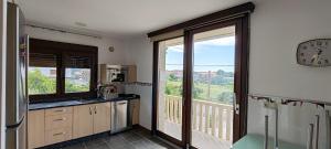 a kitchen with a large window and a clock on the wall at Casa Vilanova Costa da Morte in Cee