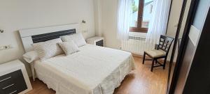 a bedroom with a bed and a chair and a window at Casa Vilanova Costa da Morte in Cee