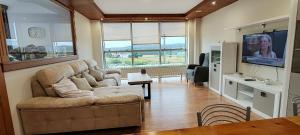 a living room with a couch and a flat screen tv at Casa Vilanova Costa da Morte in Cee