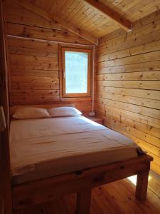 a bed in a log cabin with a window at Lada Bojana in Ulcinj