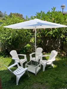 three white chairs and an umbrella in the grass at Bajo con jardín in Miengo