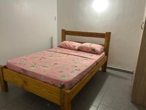 a wooden bed with pink sheets and pillows on it at Villa SCAYOU in Pointe-Noire