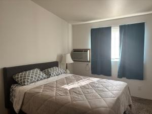 a bedroom with a bed with blue curtains and a window at Central Comfort Duplex in Moses Lake