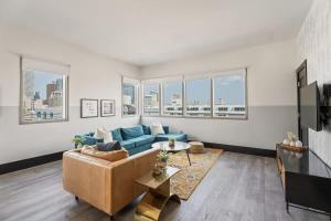 a living room with a blue couch and some windows at Corner Penthouse w Private Balcony Hotel Suite in New Orleans