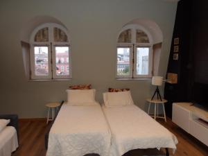 a bedroom with two beds and two windows at Oporto apartment Batalha in Porto