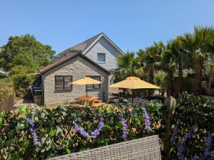 a house with umbrellas and a garden with purple flowers at Sunnycott Caravan Park in Cowes