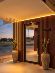 two plants in vases in front of a door at Hotel Dal Flora in Sorriso