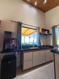 a kitchen with a counter with a microwave and a window at Sakura da Mantiqueira in Paraisópolis