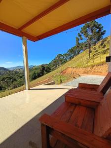 a wooden bench sitting on a porch with a view at Sakura da Mantiqueira in Paraisópolis