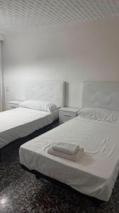 zwei Betten mit weißen Laken und Handtüchern in der Unterkunft Hostal Parada in Viladecáns + 5 Fotos