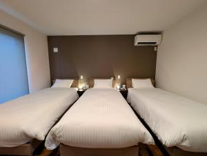 three beds in a room with white sheets at Kawaguchiko Villa LaLuce in Fujikawaguchiko