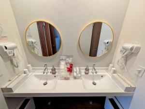a bathroom with two sinks and two mirrors at Kawaguchiko Villa LaLuce in Fujikawaguchiko