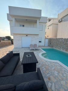 a living room with a couch and a table next to a swimming pool at AD Homes in Ravanj