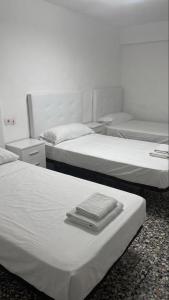 ein Zimmer mit drei Betten, auf denen Handtücher lagen in der Unterkunft Hostal Parada in Viladecáns