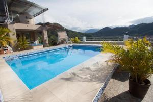 a large blue swimming pool with mountains in the background at Hotel Prince Selva Central in La Merced