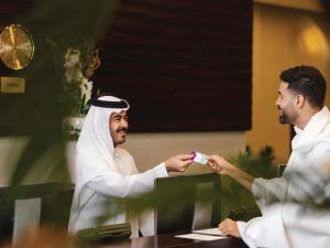 a man giving a card to a man in a room at Mercure Makkah Aziziah in Mecca