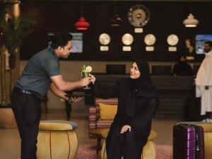 a man giving a woman a drink in a restaurant at Mercure Makkah Aziziah in Mecca