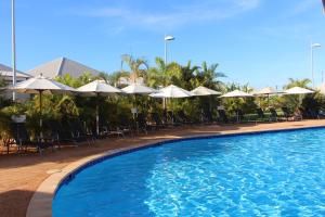 a large swimming pool with chairs and umbrellas at Exmouth Escape Resort in Exmouth