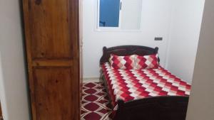 a bed in a room with a red and white pillow at Tamawanza in Aourir