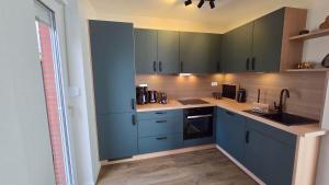 a kitchen with blue cabinets and a sink at Ferienhaus Hafenperle in Dornumersiel